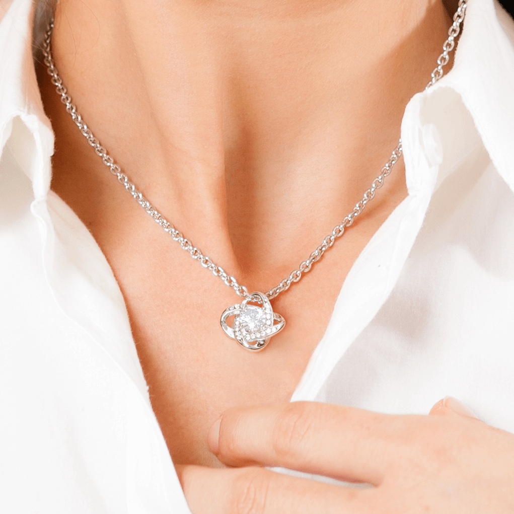 Love knot necklace worn by a woman with a white shirt